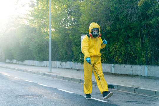 Coronavirus. A Sanitation Worker Wearing A Mask And Cleaning The Streets Radiation Virus With Pressure. Disinfecting Against To The Corona Virus. Protection Risk Control. 