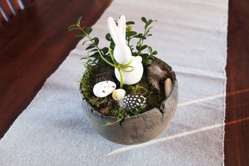 Easter home decoration on table. Pot decorated with Easter bunny and eggs. Clean, natural and modern interior design element.