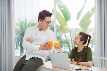 Wide shot of gorgeous lady and sir surfing in laptop while sitting at table