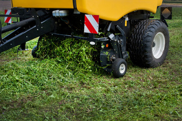 a new baler in motion work on the field creates bales from fresh silos at summer