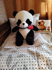 Made-up wooden baby bed with pillows and teddy panda in bedroom © Samumneo