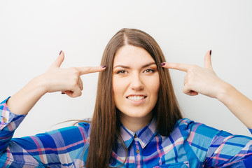Young woman holds fingers at temple isolated in white