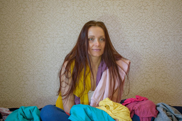 Portrait of a seated woman. A lot of women's clothing is scattered. Long brown hair, green eyes....