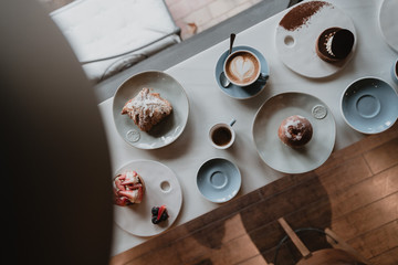 mesa con taza de café con leche, croissant, fresas y dulces de repostería