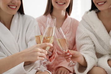 Young ladies clinking glasses of champagne at pamper party, closeup. Women's Day