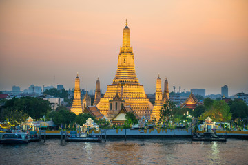 Illuminated Temple of Dawn or Wat Arun and Thonburi west bank of Chao Phraya River at sunset. Bangkok, Thailand