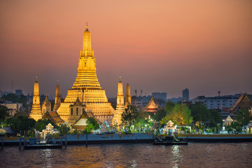 Illuminated Temple of Dawn or Wat Arun and Thonburi west bank of Chao Phraya River at sunset. Bangkok, Thailand