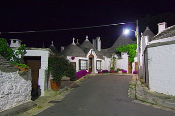 Night view of the streets with the characteristic trulli of the town of Alberobello in Puglia,...