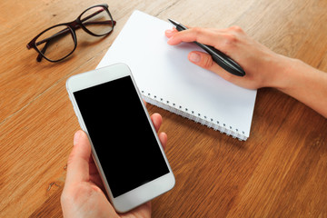 female hands holding smart phone on wooden background  , place for your text