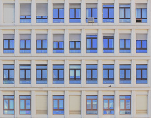 symmetrical facade of a building with blue sky reflected in the glass of the window