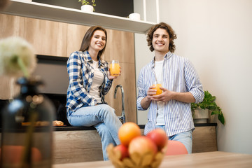 Fototapeta premium Couple eating breakfast early in the morning in the kitchen and having a good time with fresh juice