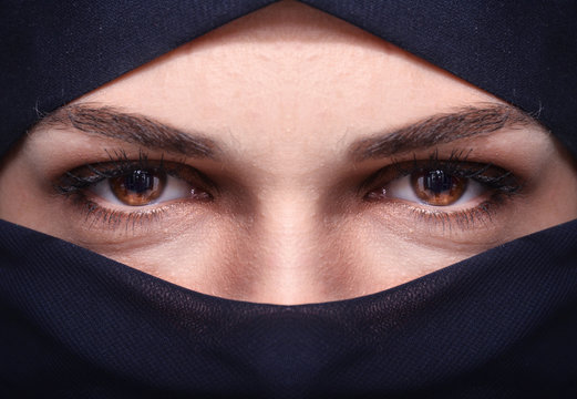 Closeup of beautiful woman face covered with hijab. Perfect brown crystal and shiny eyes of Muslim girl. Front view.