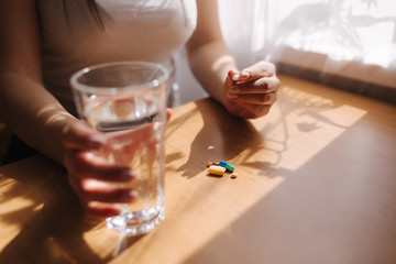 Close up of woman's hands hold pills. Hand with pills and glass of water. Immunity. Vitamines