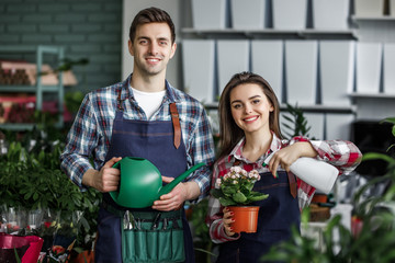 Gardeners concept, young couple  girl and man with plants in beautiful garden center or Botanical...