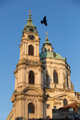 Fototapeta na wymiar facade of a historic building in the city of Prague, cream-colored facade, with green domes, a bird flies over the building
