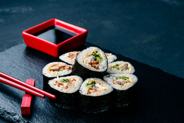 sushi on a black stone tray with chopsticks and sauce