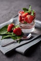 Water with strawberry and mint in sparkling glasses on gray napkin on concrete table, copy space. Cold summer drink. Mineral water