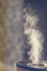 Fototapeta na wymiar Humidifier spreading steam with white brick background.