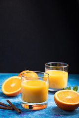 Glass of orange juice on a black and blue background. Side view, copy space.