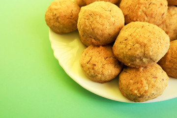 On a white plate are round biscuits made from almond nuts, eggs, butter, corn and buckwheat flour on a green background
