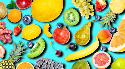 Creative photo of many different exotic tropical bright fruits with shadows on a blue summer background. View from above. Bright summer fruit pattern.