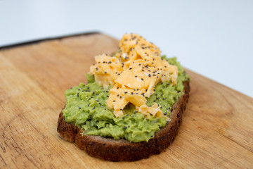 whole wheat toast with guacamole and omelette on top of a wood