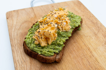 whole wheat toast with guacamole and omelette on top of a wood