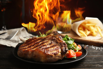 Tasty beef steak and flame on black wooden table