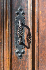 Ancient forged door handle on a aged wooden door