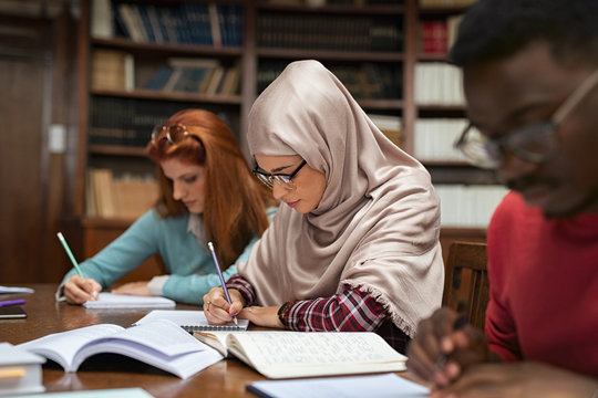 Muslim young woman studying with classmates