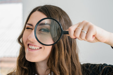 on a gray background young girl looking through a magnifying glass
