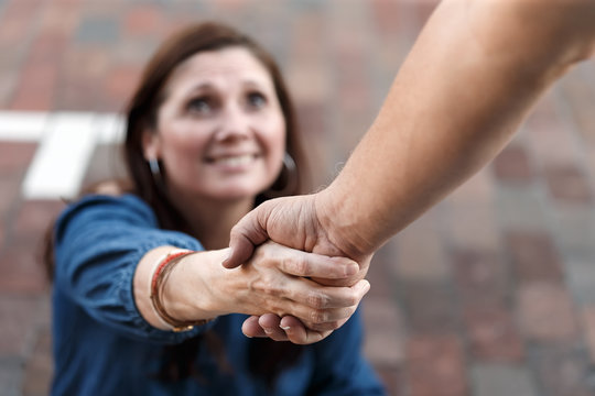 Man giving woman a friendly helping hand to lift her up to help and support her to get her on her feet in fellowship