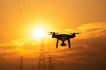 Drone surveying High voltage towers the sunset background