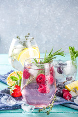 Summer cold drink concept. Fruit and berries gin tonic cocktail, or infused water lemonade mocktails, with fresh blueberry, raspberry, lemon and herbs, blue green old wooden background copy space