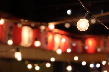 close up light bulb in Japanese night market. Blur red and white Japanese lanterns as background