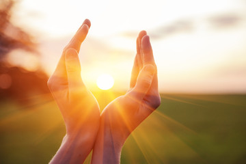 Plakat young woman raising hands praying at sunset or sunrise light