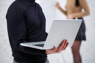 Manager businessman male announcer stands with a laptop while a woman writes a business promotion...