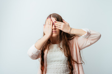 Naklejka premium on a gray background young girl closes eyes with her hands