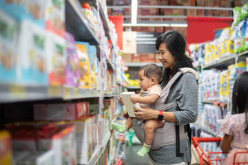 asian mother buying baby product while carrying her daughter