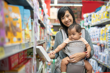 Obraz premium asian Mother and baby shopping in the supermarket. grocery store shopping