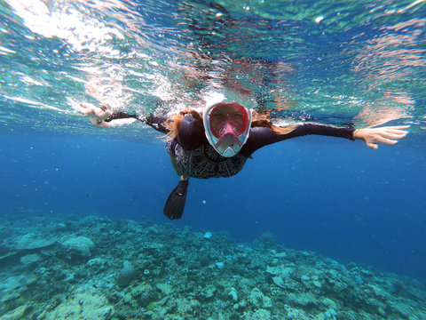 Woman enjoying swimming with scuba mask, exploring sea life. Underwater photography on coral reef. Snorkel water sport. Maldives