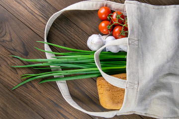 Woven bag of different health food on dark wooden table background. Bread, green onion, garlic,...