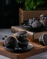 chocolate vegan muffins on a wooden background. Blueberry  on side. Dark and moody photo style.
