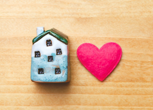 sweet home concept, mini toy house and red heart on wooden background, top view, flat layout