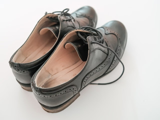 Overhead view of a ladies pair of classic well worn black leather heeled brogues on a plain white background
