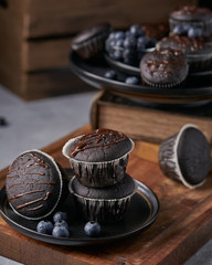 chocolate vegan muffins on a wooden background. Blueberry  on side. Dark and moody photo style.