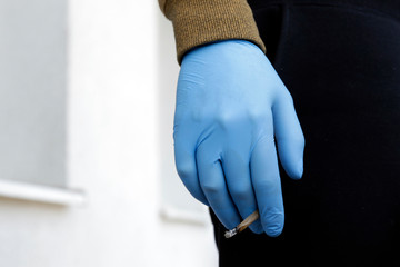 Man in protective gloves with cigarette. Covid-19 daily life. Protect from corona virus and smoking. Smokers facing higher risk of severe symptoms caused by corona virus. 