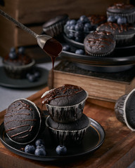 chocolate vegan muffins on a wooden background. Blueberry  on side. Dark and moody photo style.