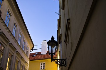 Fototapeta na wymiar Isolated black street lantern hanging on the wall in a narrow street (Prague, Czech Republic, Europe)