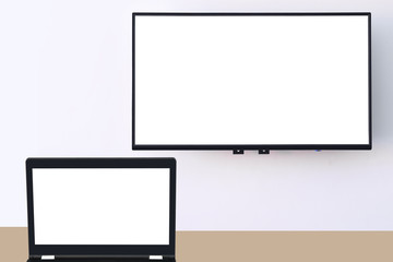 White screen computer on the table and white wide screen smart TV digital hanging on white wall background, copy space input text concept and smart technology idea